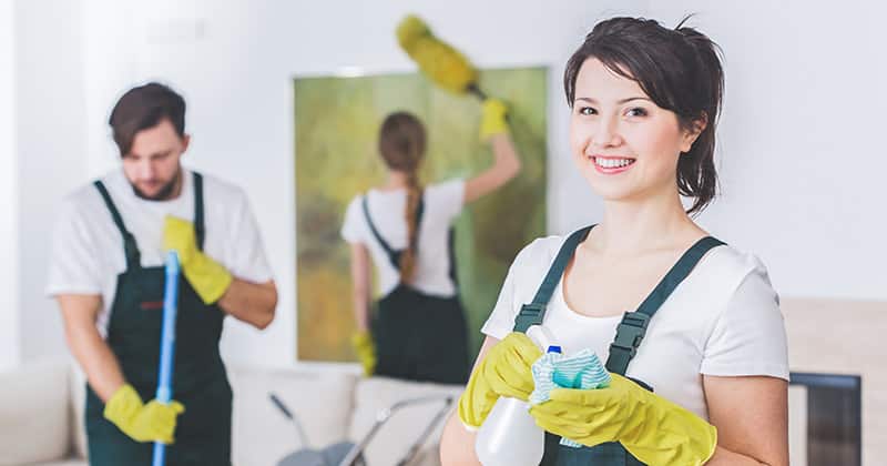 Group of cleaners and woman smiling at camera