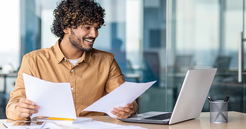 Young worker looking at invoice and laptop